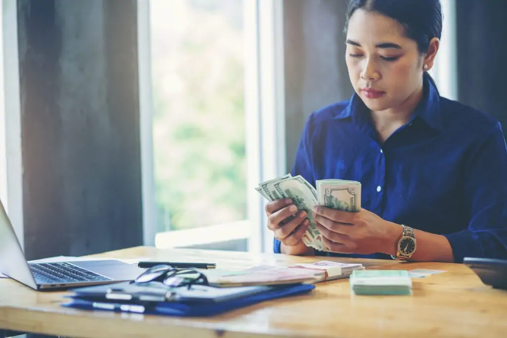 business-woman-on-computer-holding-cash