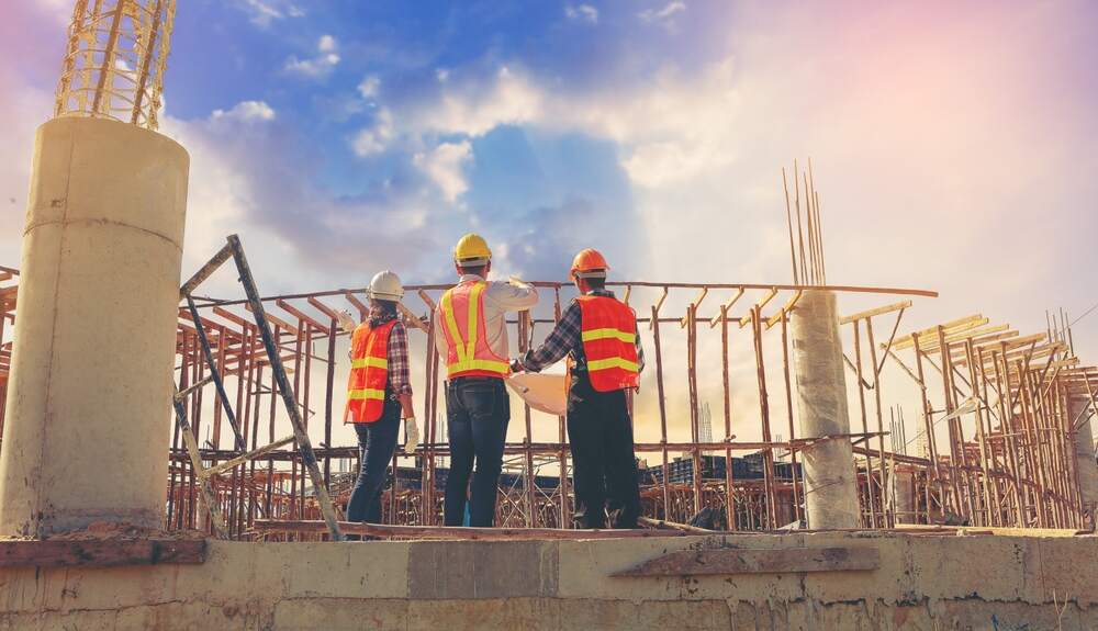 Construction workers at a job site reviewing blueprints