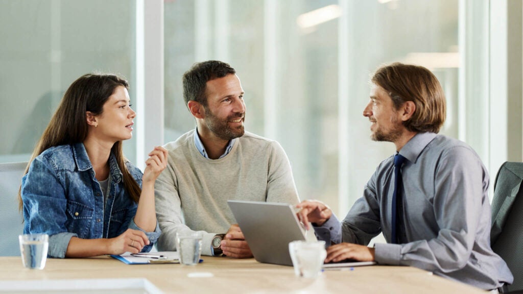 Two people review and sign a term loan with a lender representative.